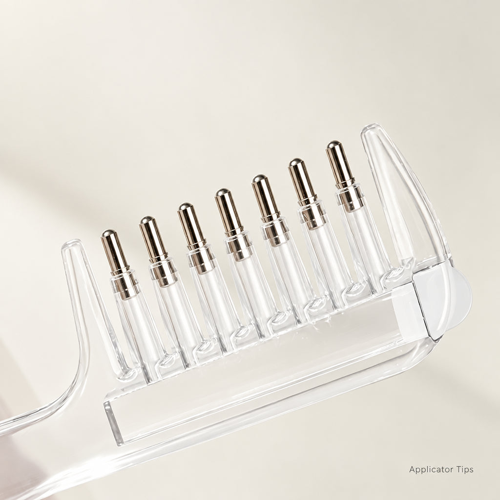 A clear liquid comb with metallic teeth shown on a light neutral background.
