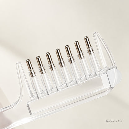 A clear liquid comb with metallic teeth shown on a light neutral background.