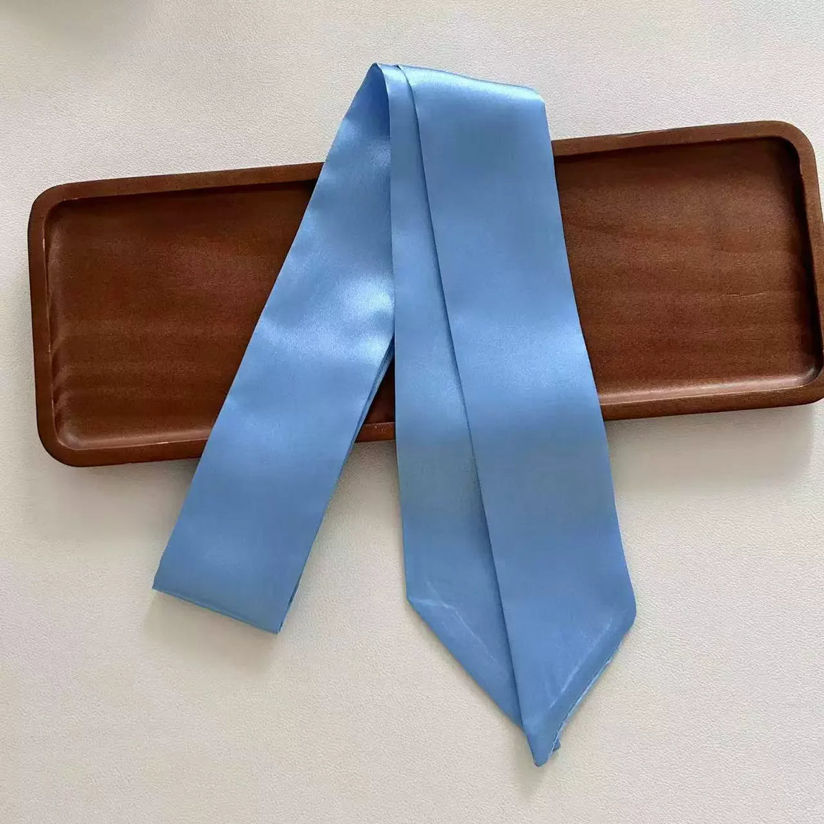 Light blue ribbon on a brown tray with a white background