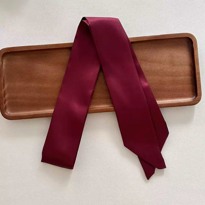 Maroon scarf draped over a wooden tray on a light background