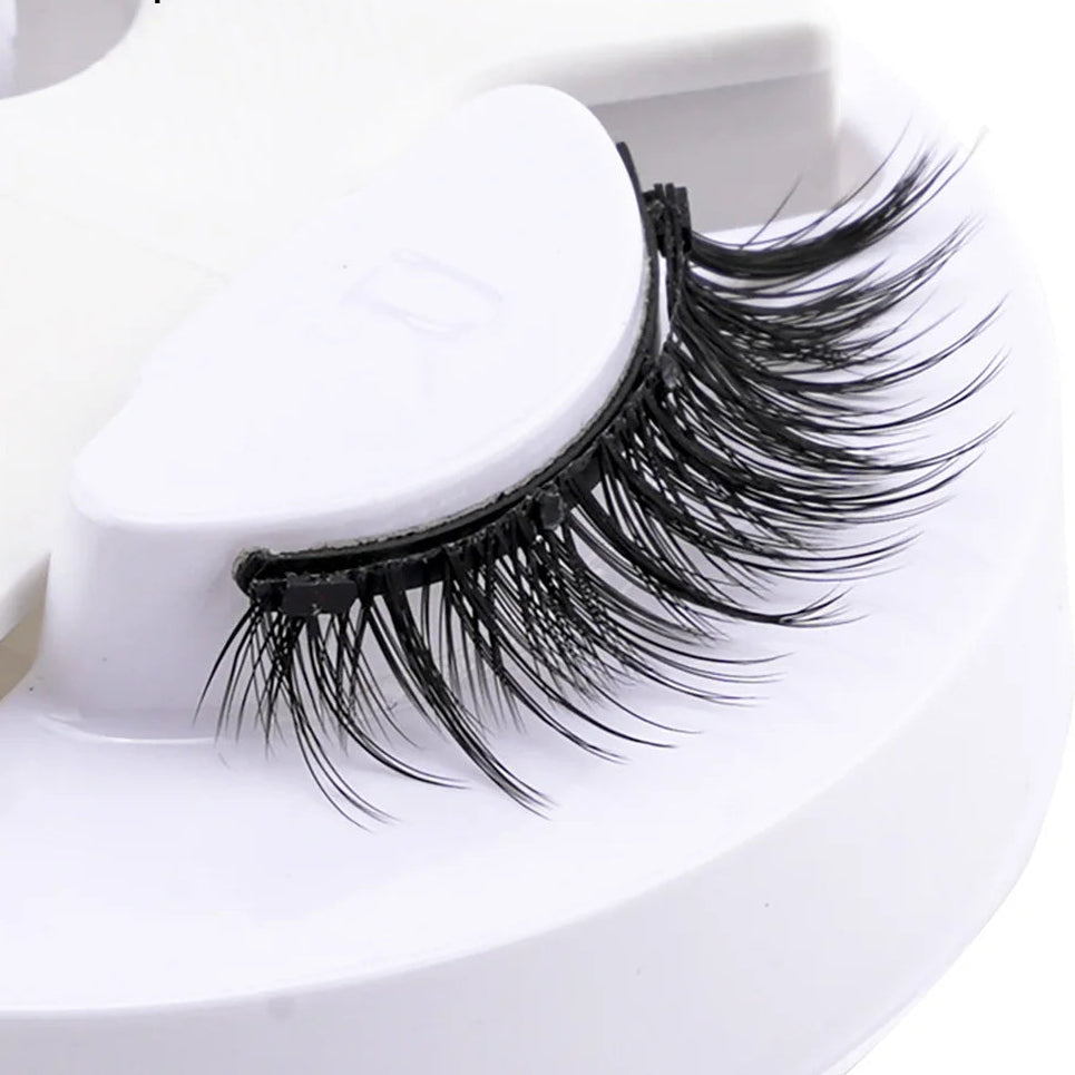 Pair of false eyelashes on a white stand.