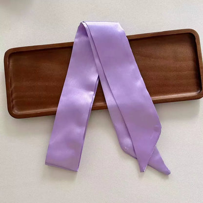 Purple satin ribbon on a wooden tray with a light background