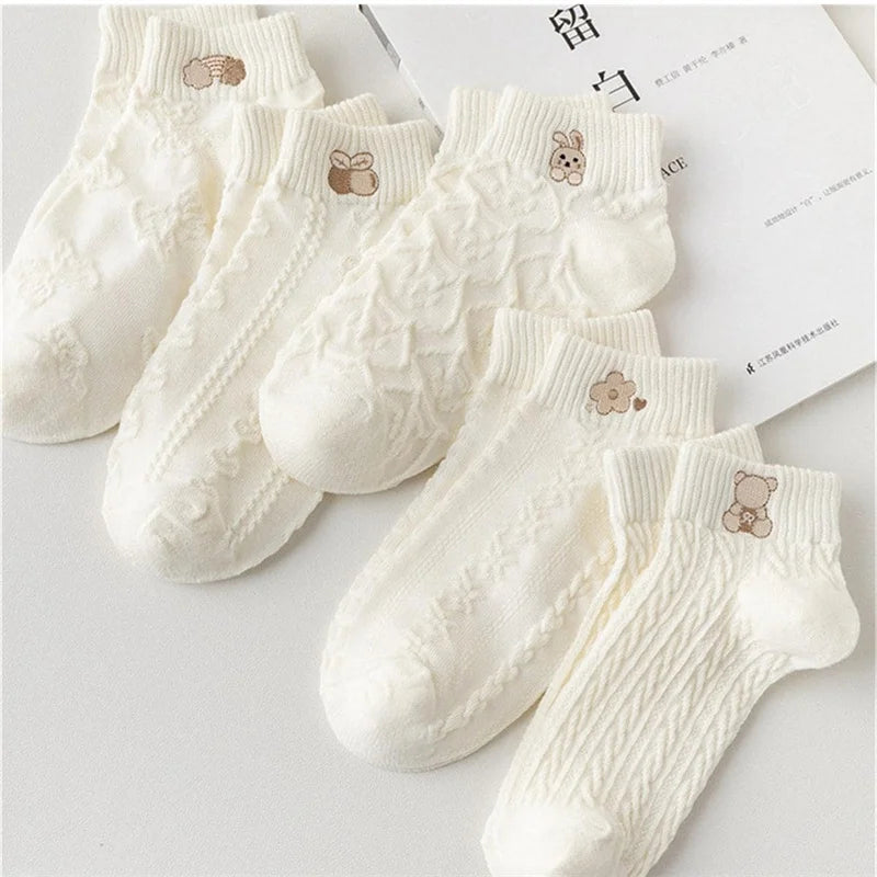 White textured ankle socks with cartoon cuff motifs arranged on a light surface.