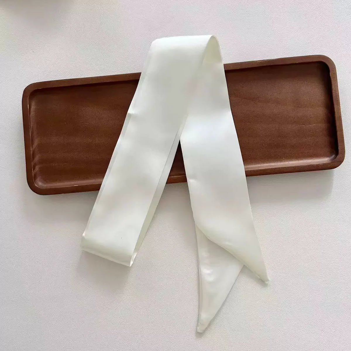 White ribbon tied in a bow on a brown tray with a white background
