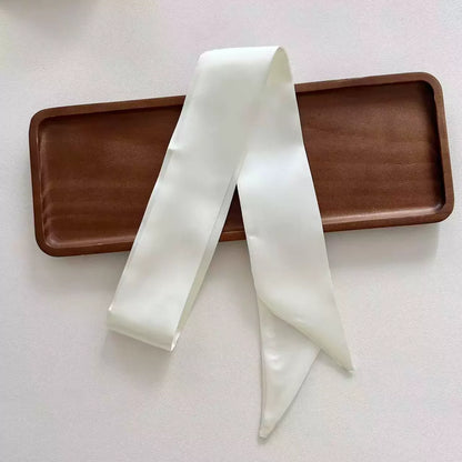 White ribbon tied in a bow on a brown tray with a white background
