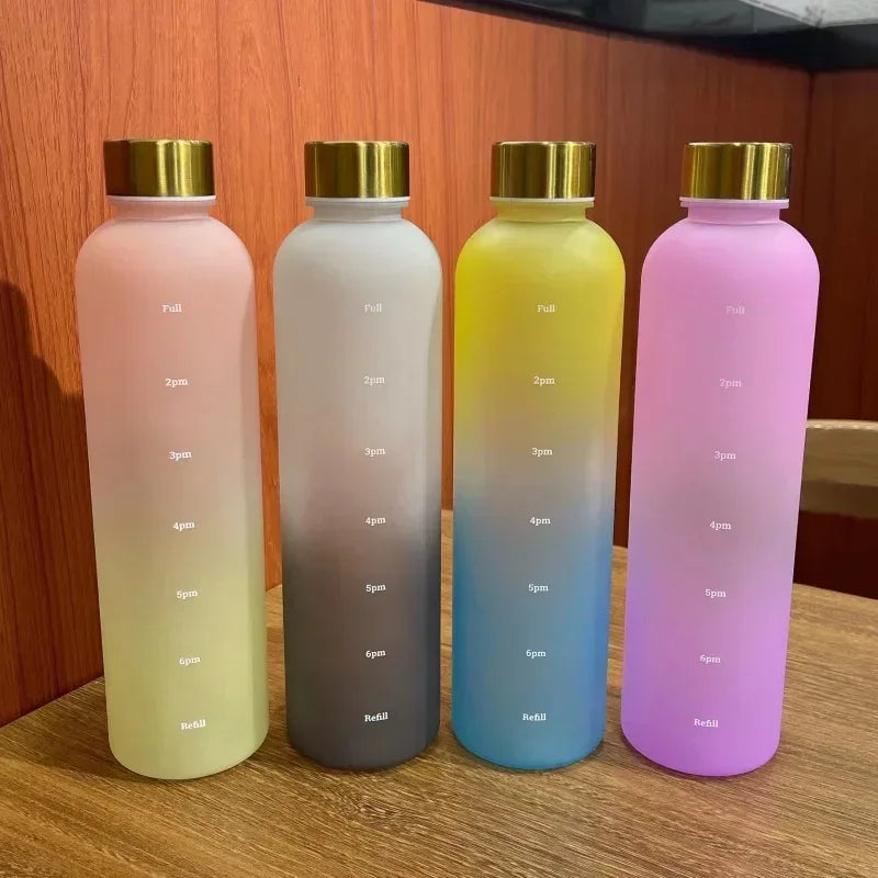 Four gradient-colored water bottles with gold lids on a wooden surface.